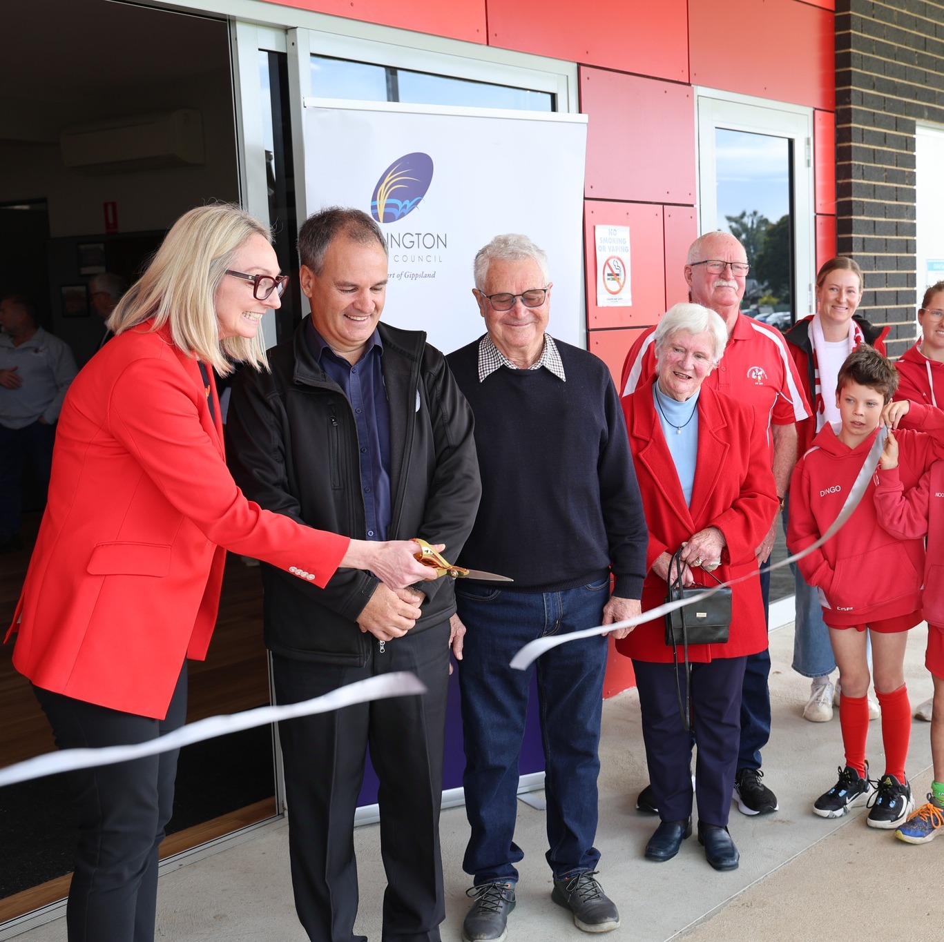 Lisa standing with members of a local football team, cutting a ceremonial ribbon.